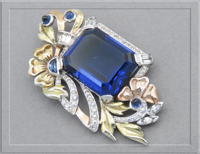 Glass sapphire set in tri-gold tone setting with sapphire bullet cabochons